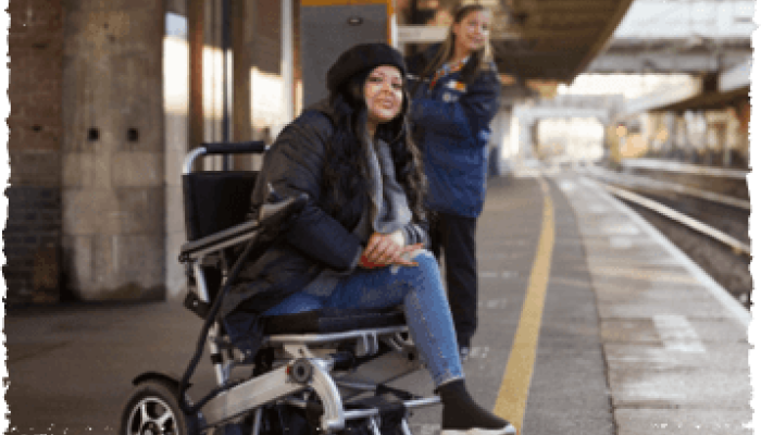 Wheelchair assisted passenger waiting for the train and a railway staff holding a ramp